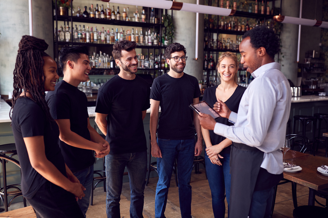 Male Restaurant Manager with Digital Tablet Giving Team Talk to